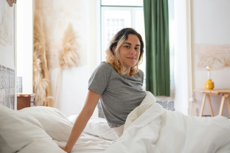 a smiling girl on a bed with all white sheets