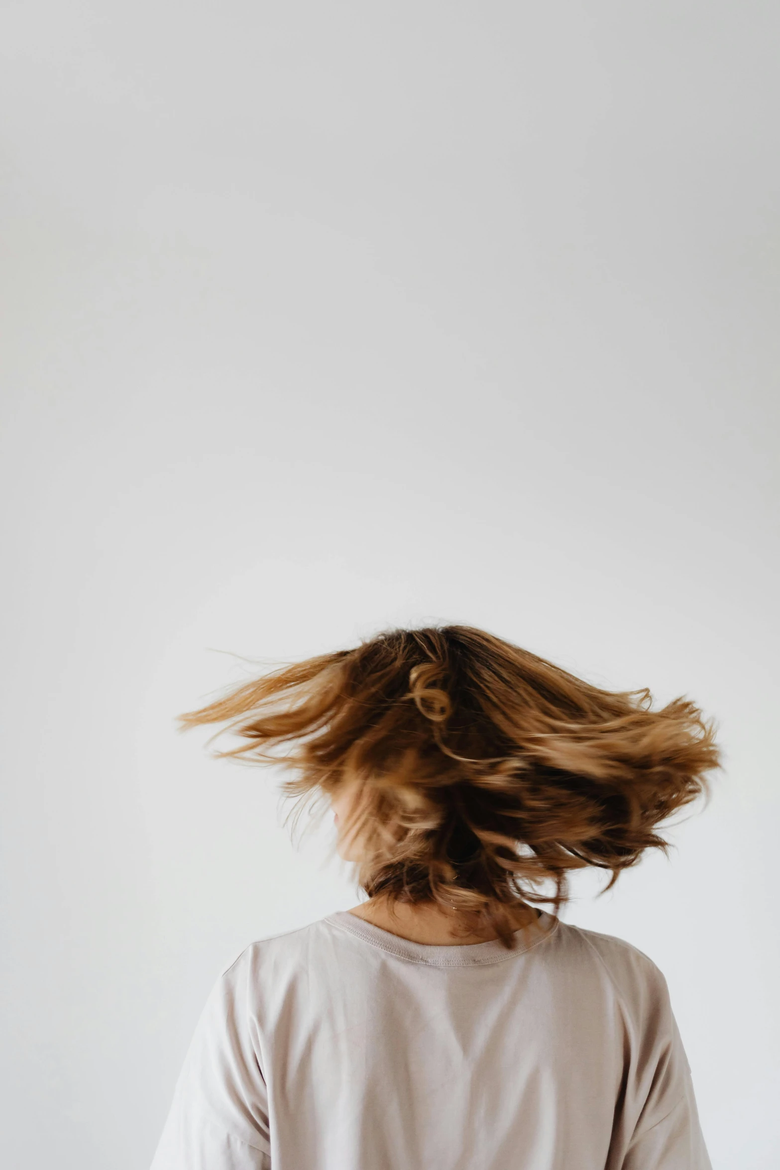 a girl wearing white is standing by the white wall