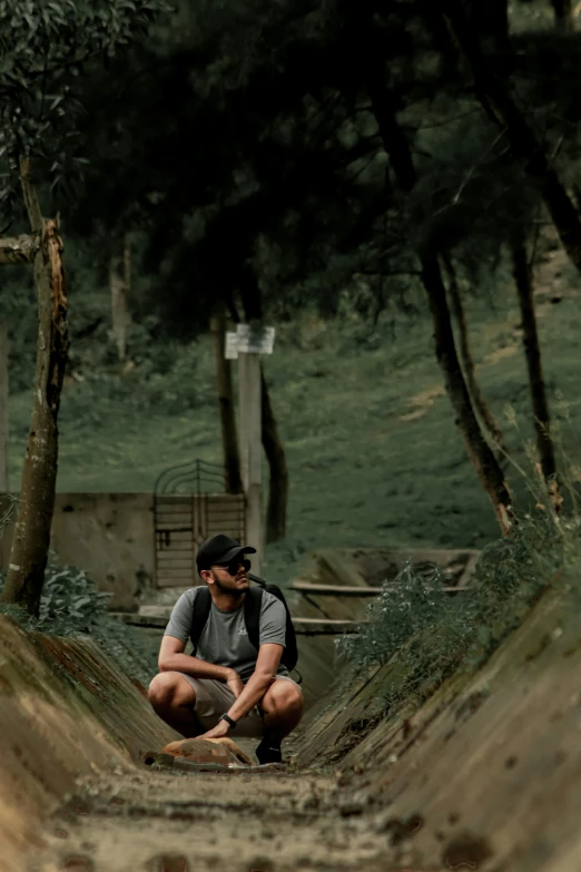 a man kneeling down by some trees in the forest