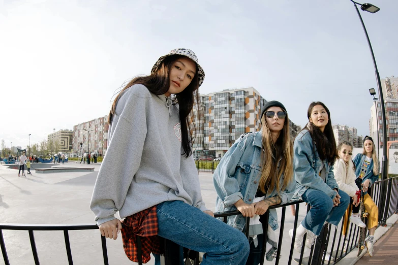 four girls sitting on railing next to skateboard park