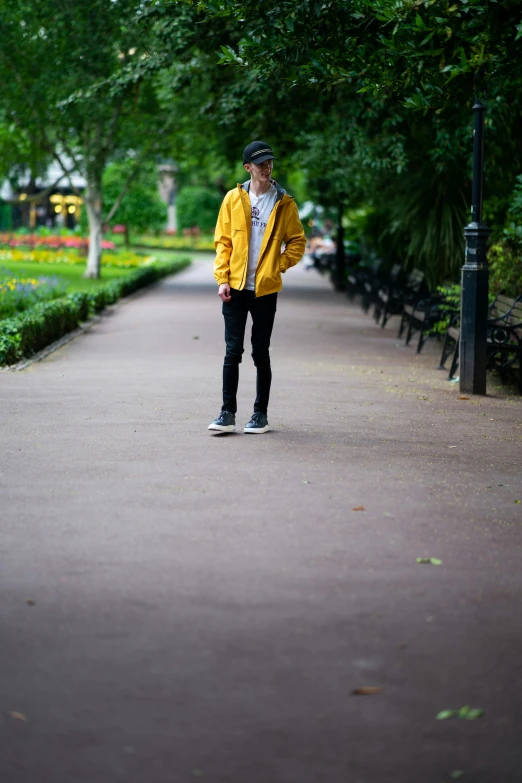 a person in yellow jacket with skateboard by trees