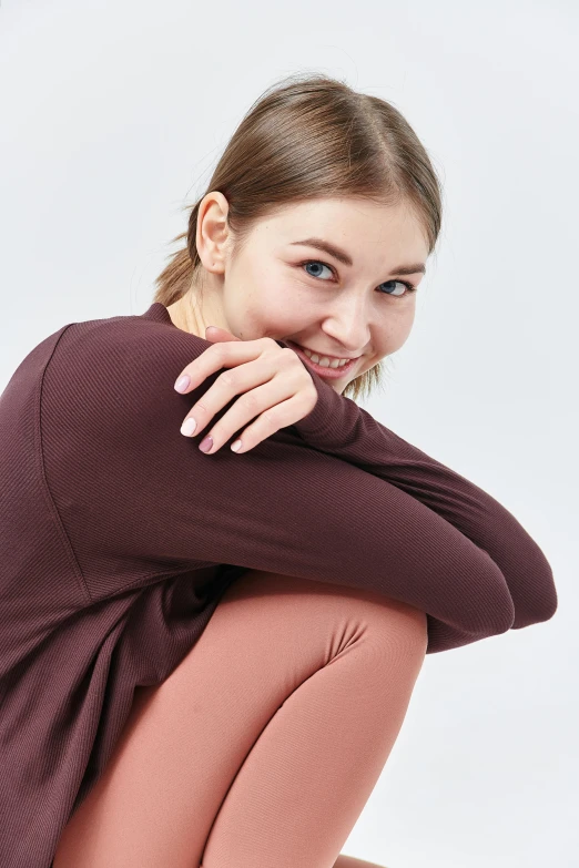 a woman in brown is smiling and sitting on the ground