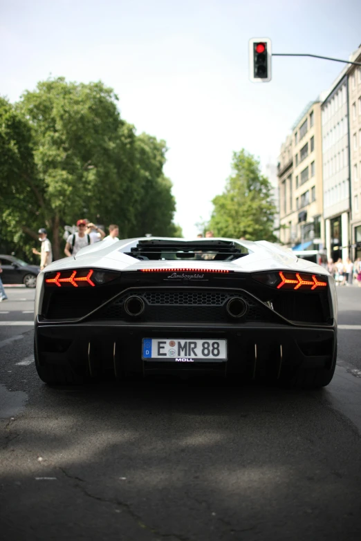 a supercar sitting on the street waiting for a traffic signal
