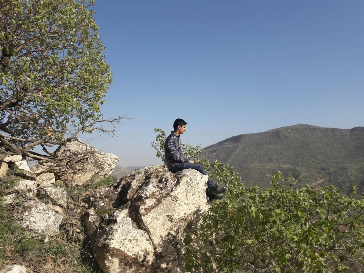 man sitting on top of a mountain and looking out