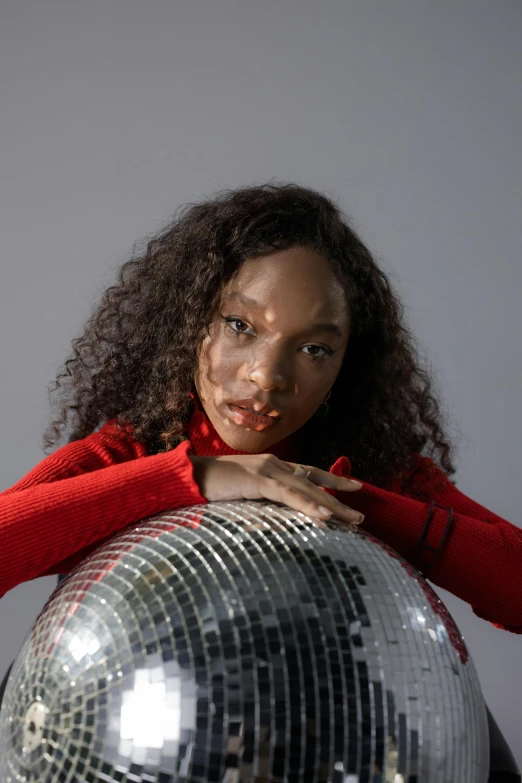 a girl with red shirt leaning over disco ball