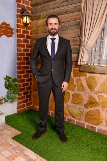 a man in a suit stands by some grass