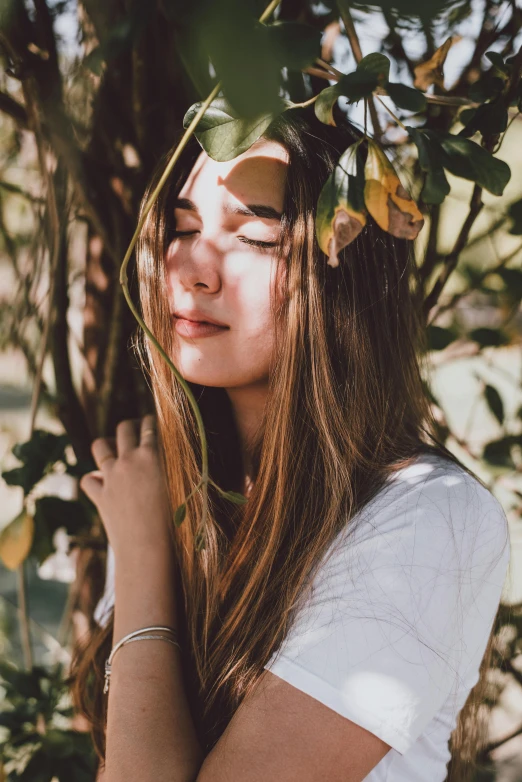 a girl is standing in front of a tree