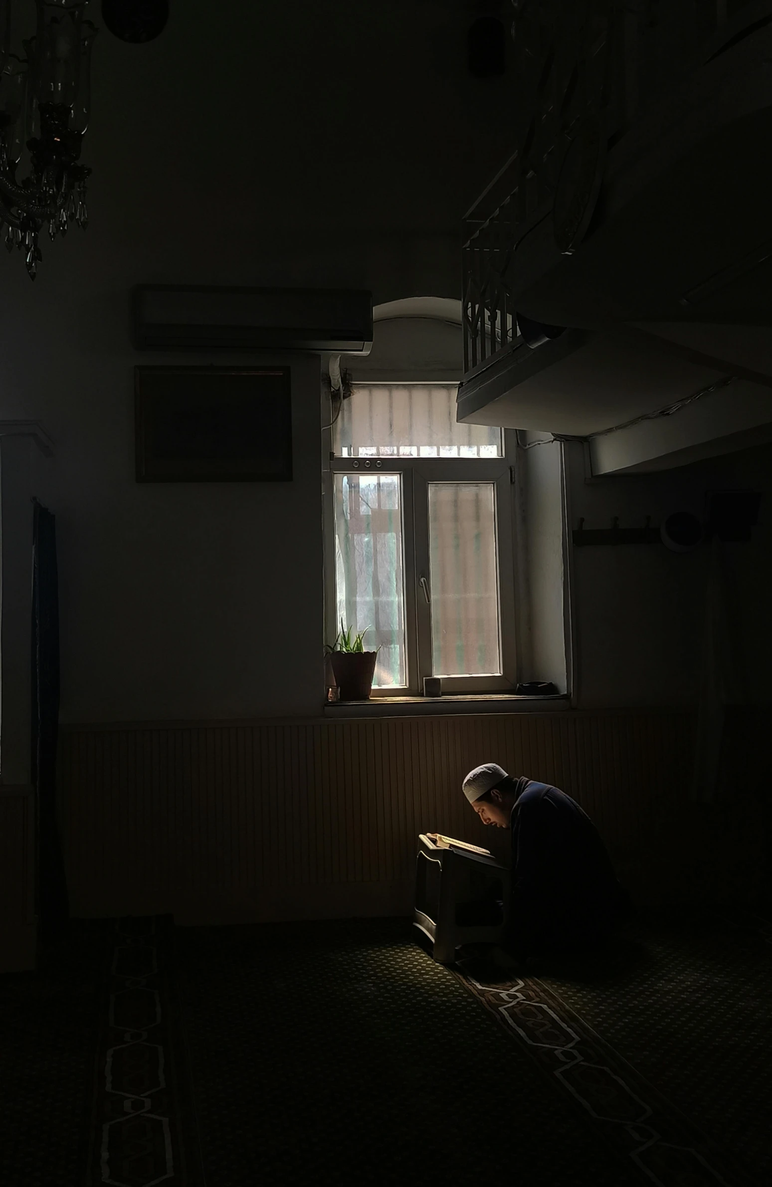 a person kneeling down in the dark near a window