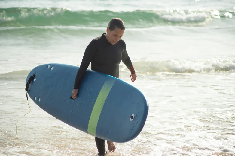 a person walks in the water carrying a surf board
