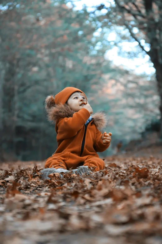 a baby doll that is sitting in the leaves