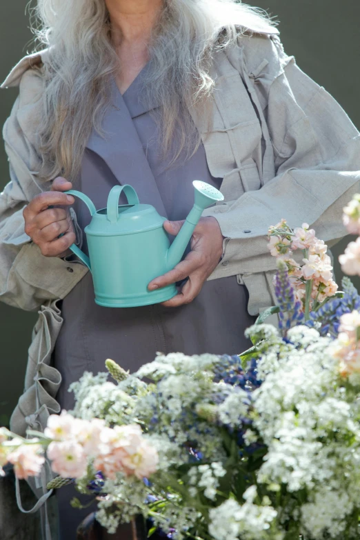 woman with gray hair wearing a light blue watering can