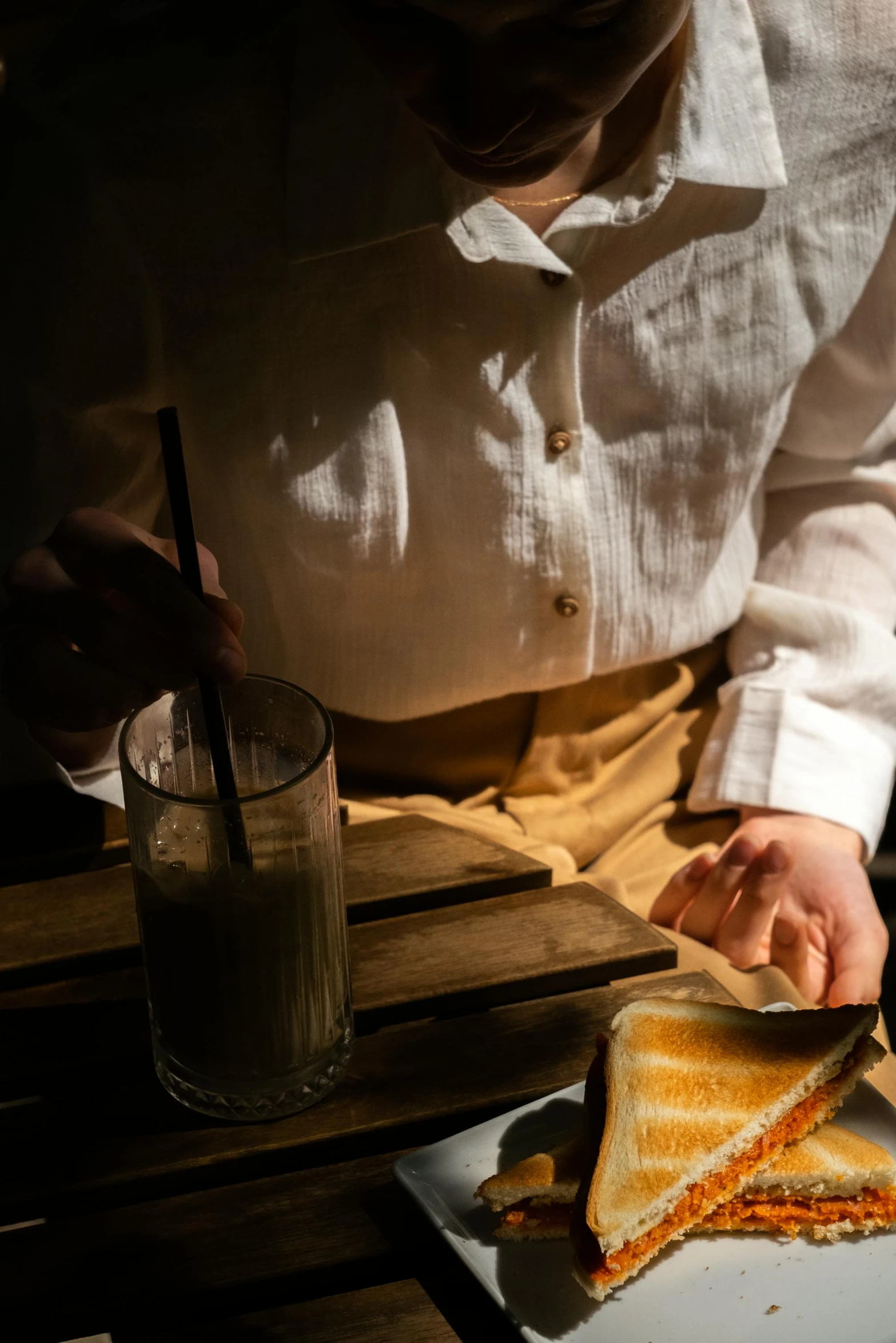 a man in white shirt eating a sandwich and drinking drink