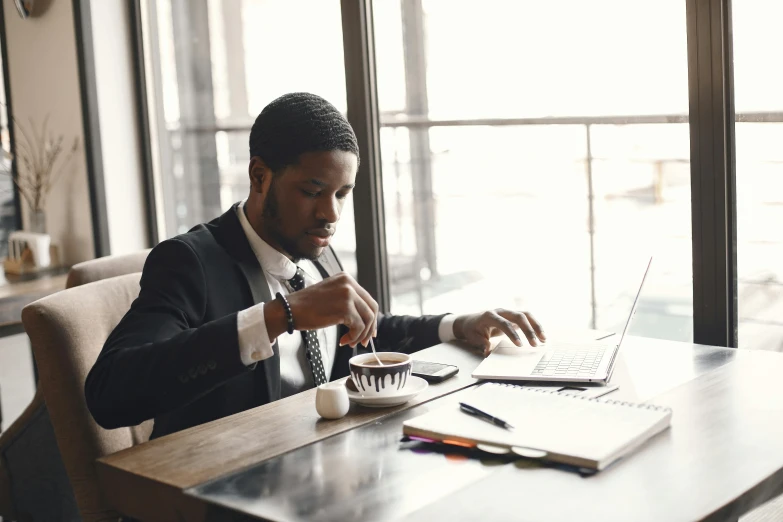 man in suit with laptop and cup of coffee