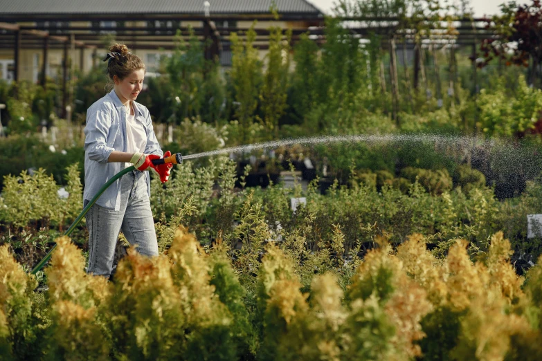 a young woman is watering plants in a garden