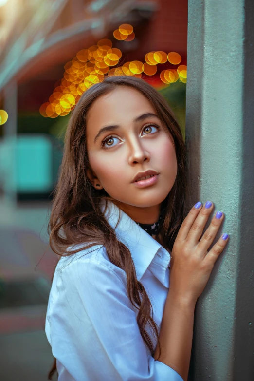 a beautiful young woman leans against the wall with her arms crossed