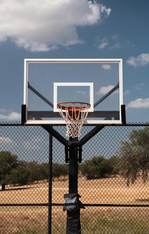 basketball hoop on the top of a fence with a sky background