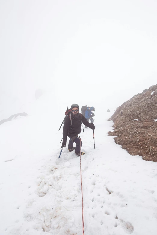 man walking up the side of a snow covered mountain in gear