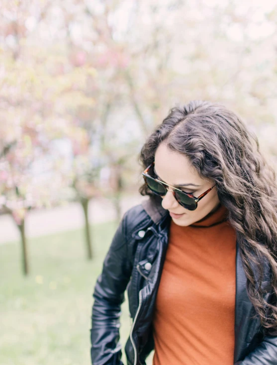 a woman with brown hair wearing an orange shirt and black leather jacket