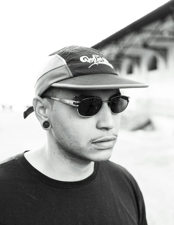 a man wearing sunglasses and a cap standing in front of a building