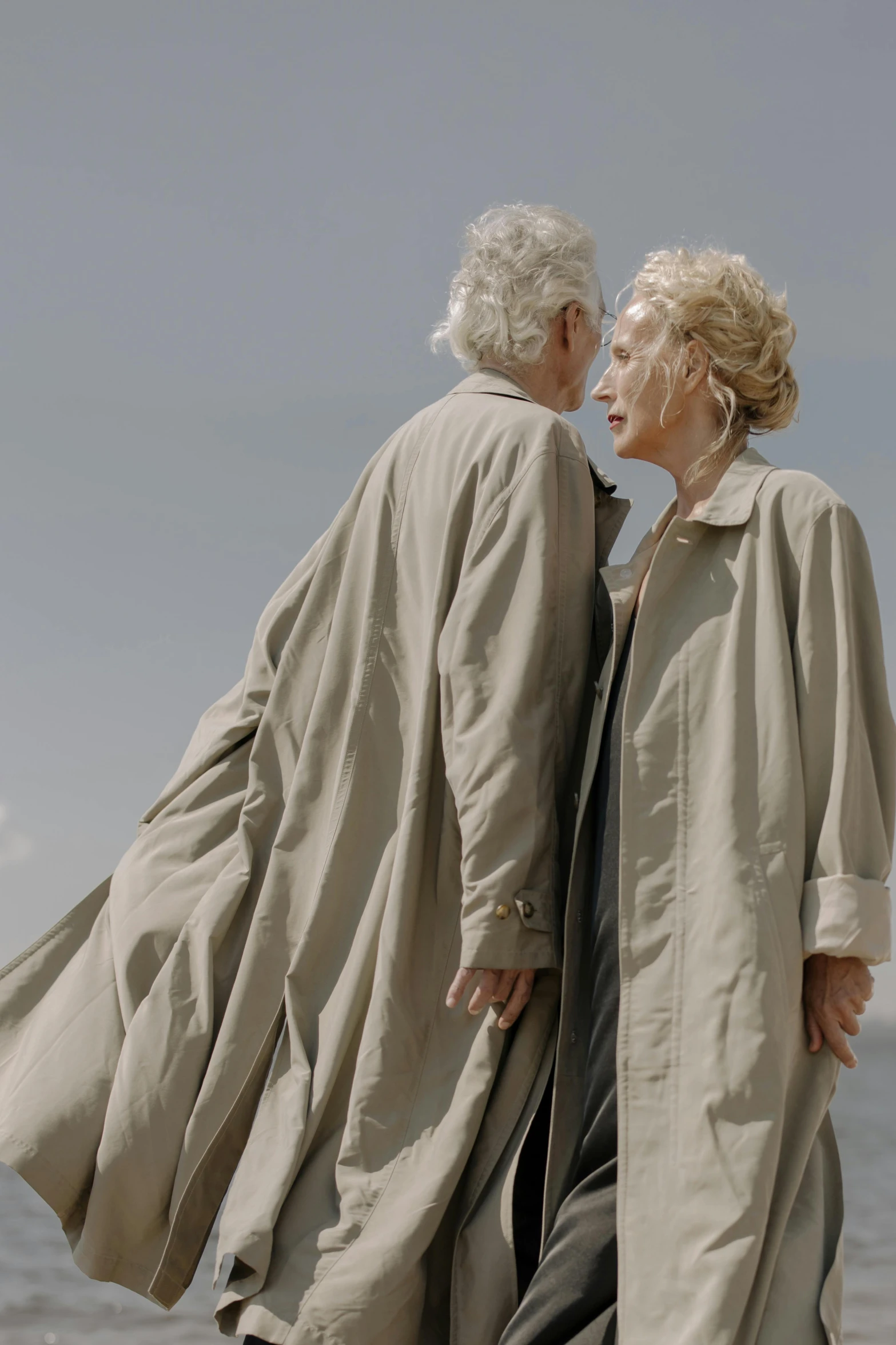 an old couple walking on the beach holding hands