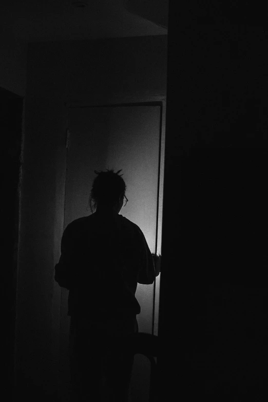 the dark silhouette of a man standing against a door