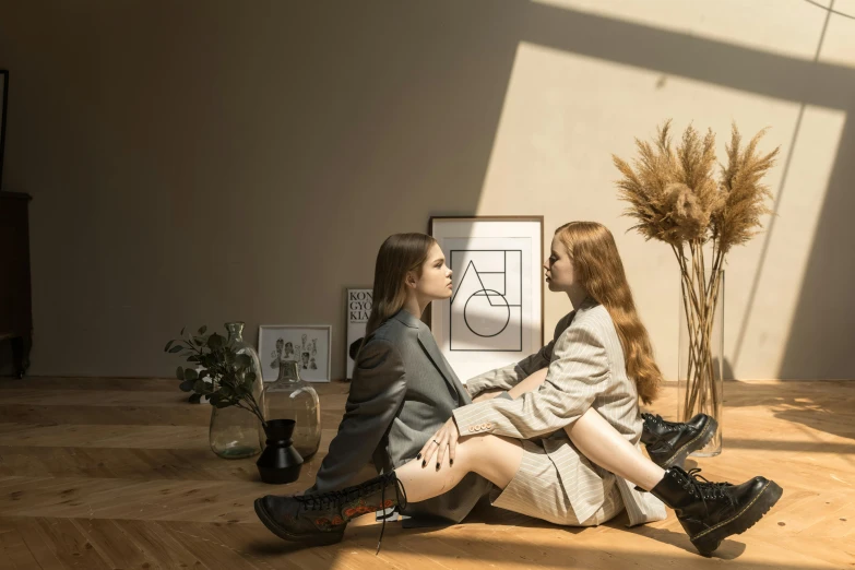 two young women sit on the floor, looking at each other