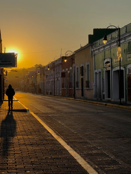 person standing alone in front of row houses at sunset