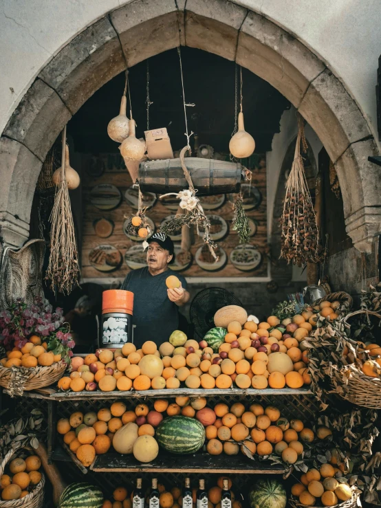 a street vendor selling oranges and watermelons in front of an arch