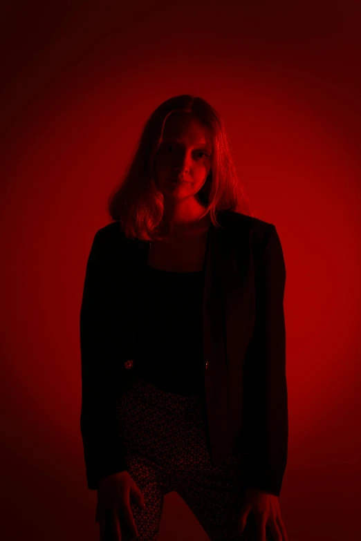 woman in black jacket standing in red background