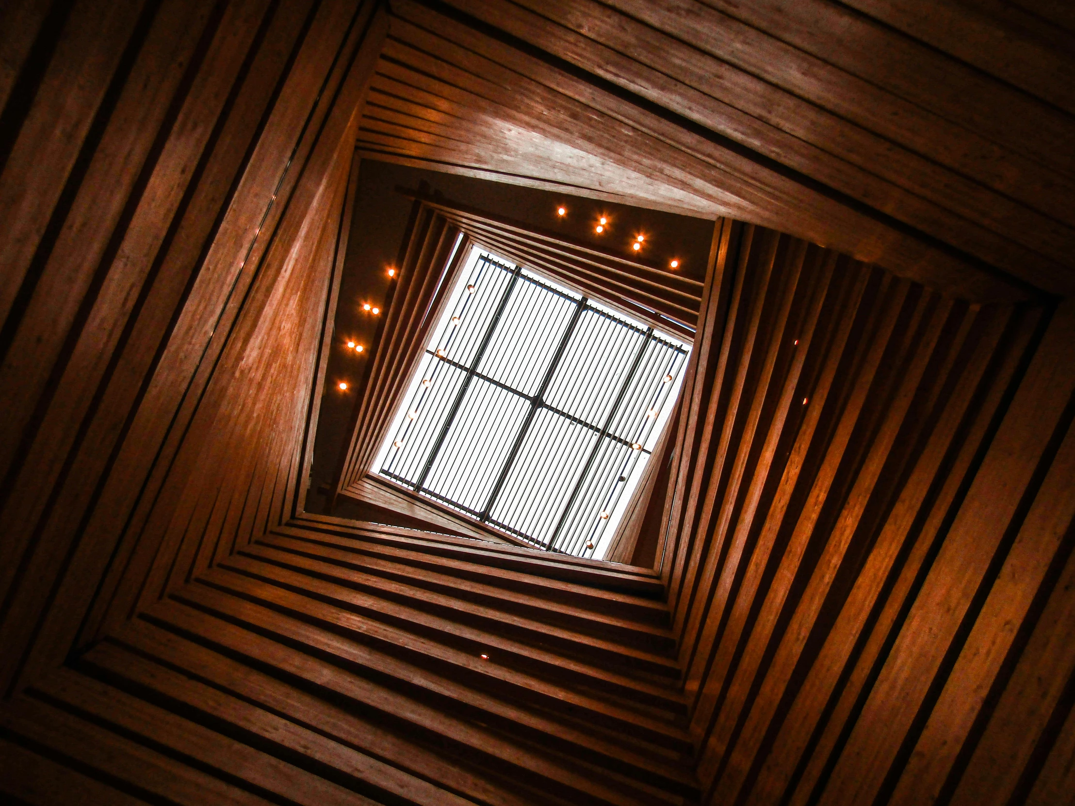 an upward s shows a window and lights in a wooden wall