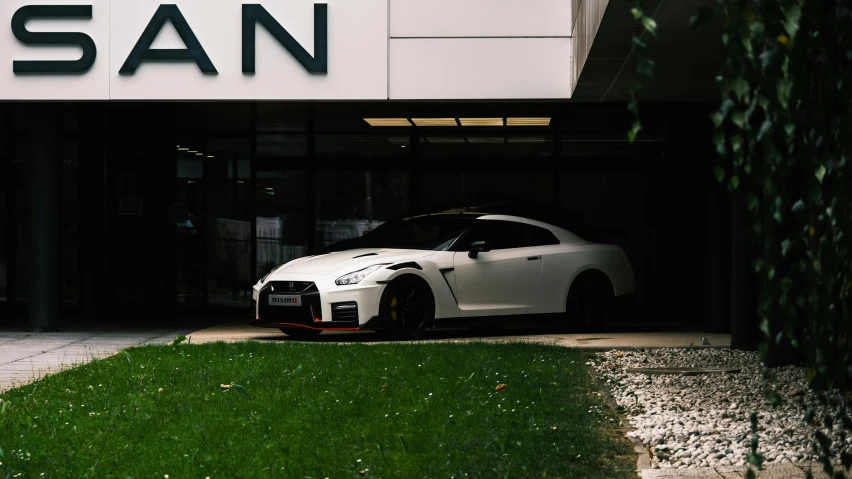 a white car parked outside a building with the name nissan on it