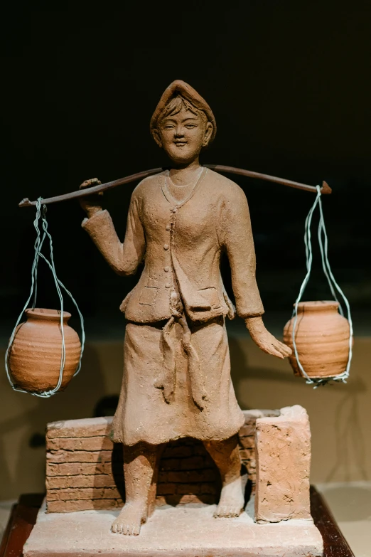 a clay statue holding two lamps and balancing it on one leg