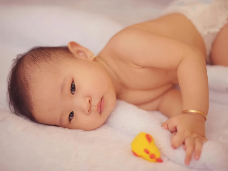 baby laying on white blanket smiling at camera