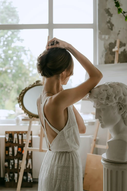 a woman wearing a wedding dress standing next to a statue