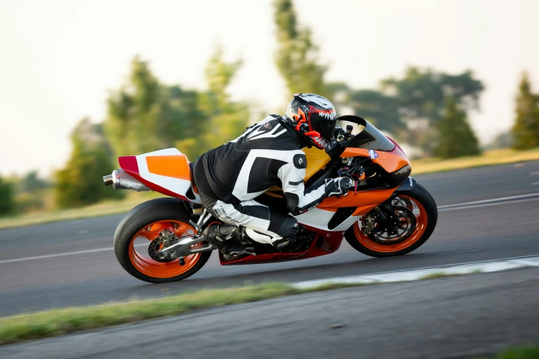 the motorcycle racer is wearing a white, orange, and black suit