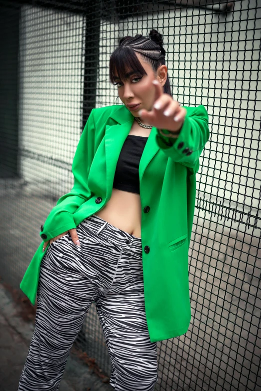 a woman wearing green is standing near a fence