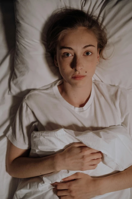 a girl laying in bed with a white shirt on