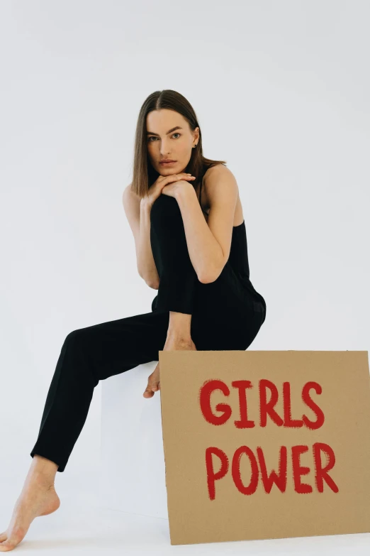 a  sits holding a sign that says girls power