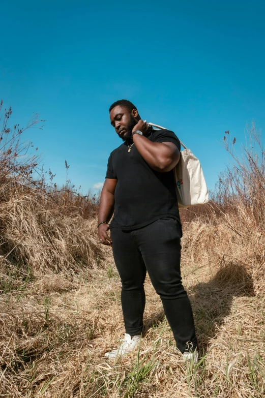 a man standing in a field talking on a cell phone