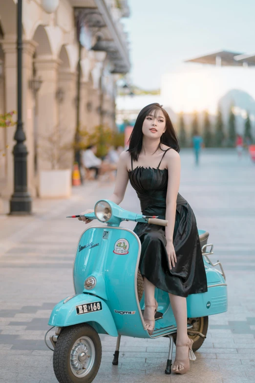 an asian woman in black sits on a blue moped
