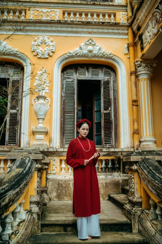 an asian woman standing at the front of a yellow and white building