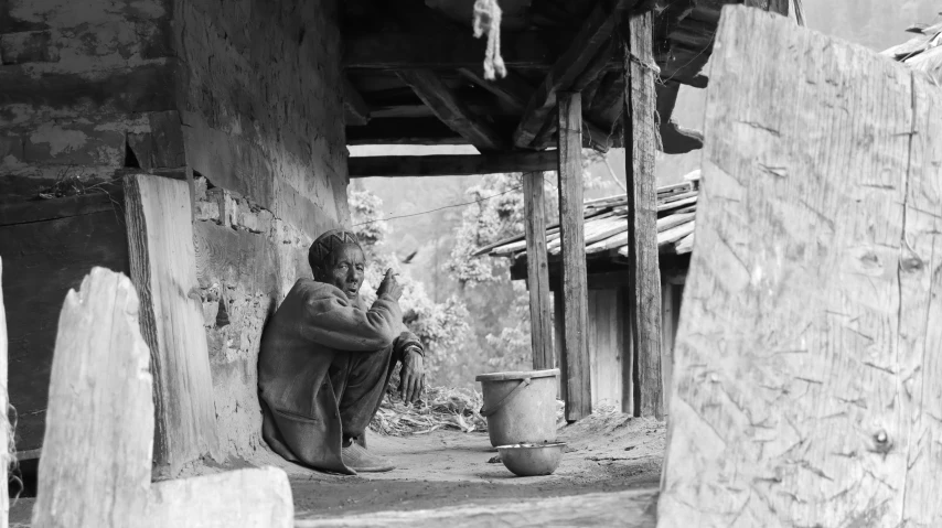 a man with his hands crossed sitting in the dirt