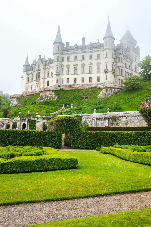 a view of the back of a large, two story building that has gardens in front and on the other side