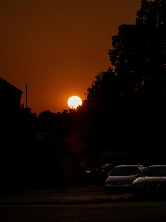 the sun shines in the sky behind some trees