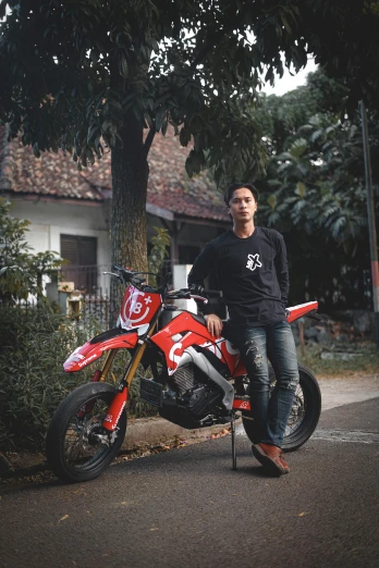 a man posing next to a motorbike in the street