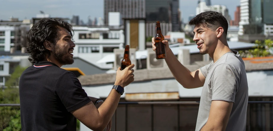 two men are holding their beers and laughing