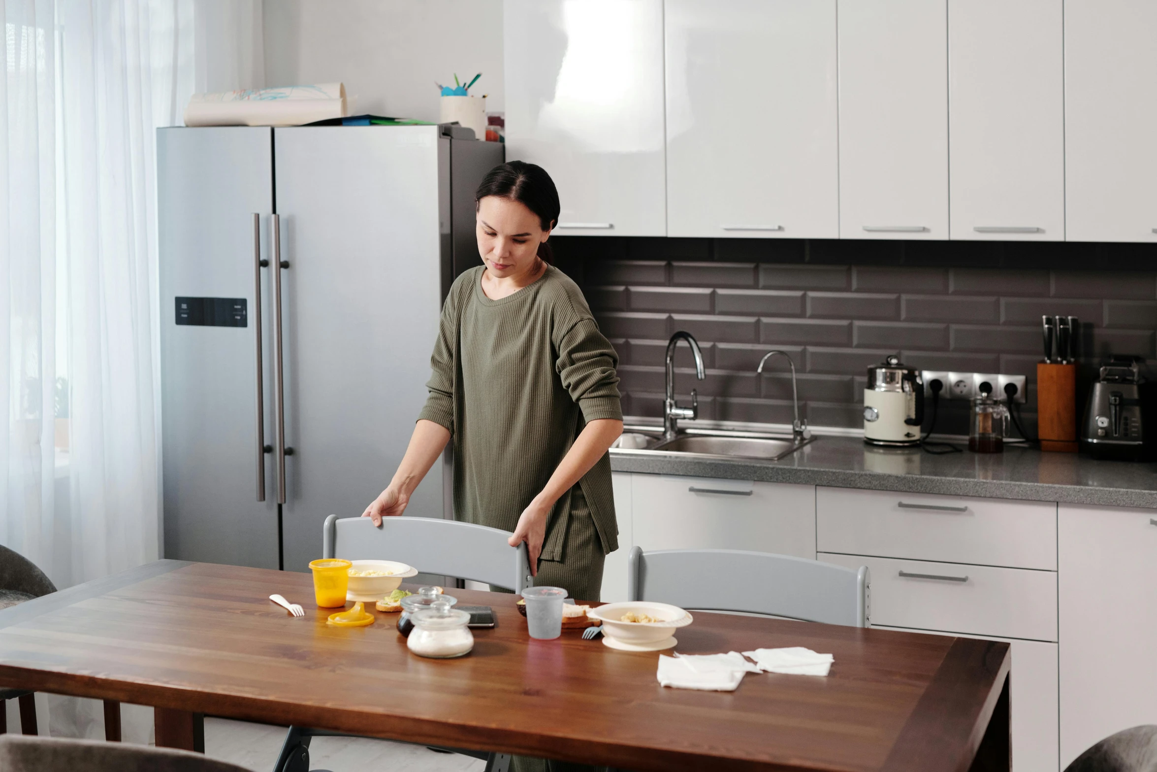 a woman using a kitchen table with a plate on it