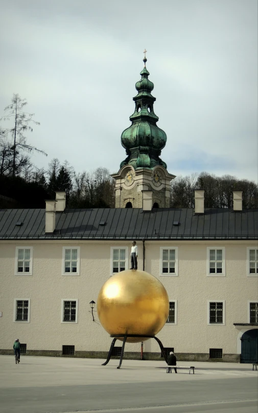 a large gold round object sits on a sidewalk