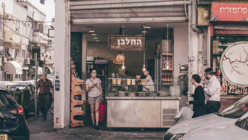 some people stand at a food kiosk in a busy street