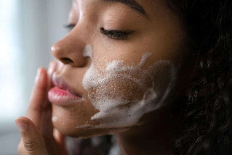 woman shaving her face with white foam on it